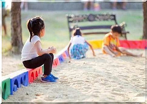 Friends - child sits alone at the sandpit