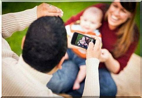 Father takes a cell phone picture of his baby.