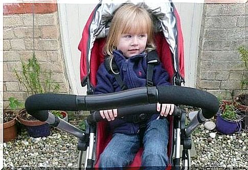 Little girl is sitting in stroller.